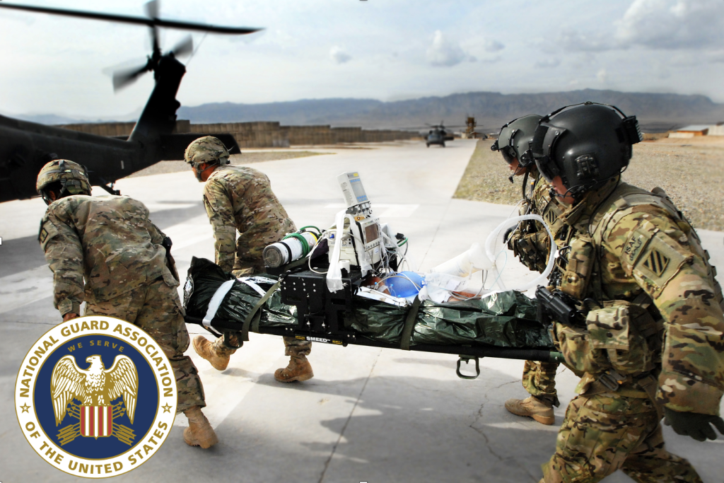 U.S. National Guard soldiers in tactical gear carry a medical stretcher with a simulated patient to a helicopter during a training exercise.