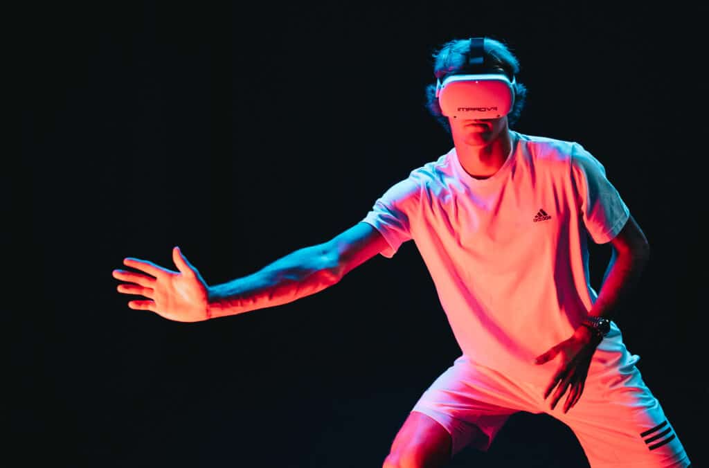 A person wearing an IMPROVR virtual reality headset performs an athletic motion in a dark environment illuminated by dynamic lighting.